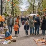 Koningsdag vrijmarkt waar kinderen en gezinnen tweedehands spullen verkopen